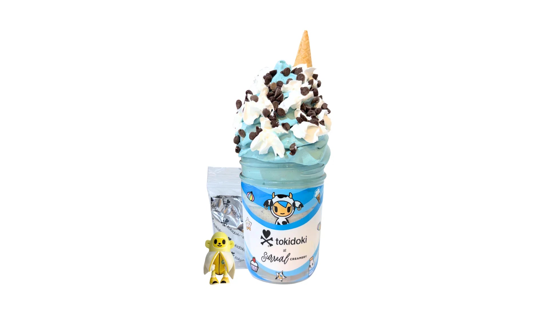A tokidoki inspired Breaking Batter Ice Cream Cake Jar with Vanilla Cake, Cookies and Cream & Blue Vanilla Frosting, Chocolate Chips, Whipped Cream and Monster Cookie Ice Cream. Served in a limited-edition mason jar and paired with one 1" tokidoki mystery collectible.