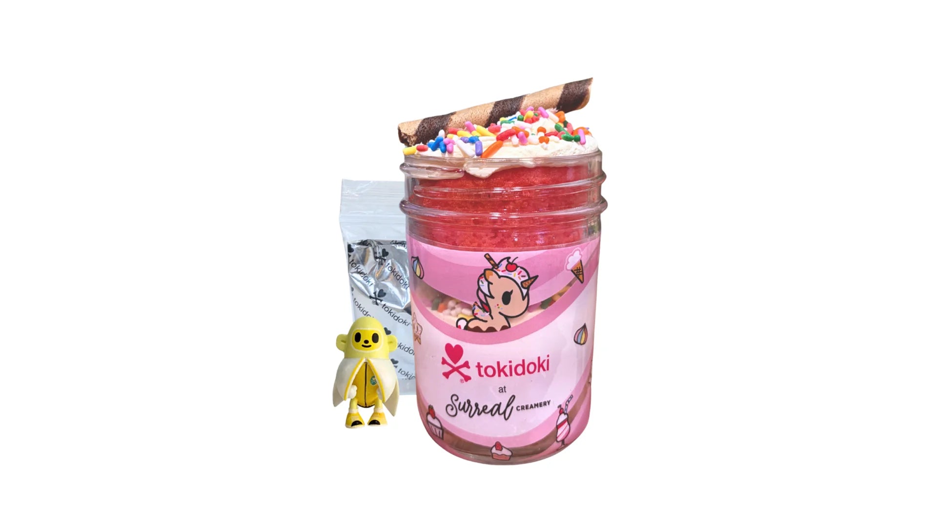 A tokidoki inspired Breaking Batter Cake Jar with Vanilla Cake, Strawberry Cake, Cream Cheese Frosting, Rainbow Sprinkles and Chocolate Straws. Served in a limited-edition mason jar and paired with one 1" tokidoki mystery collectible.
